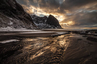 Atemberaubende Landschaft von Meer und felsigen Bergen mit Schnee unter bewölktem Himmel in Norwegen im Winter Sonnenuntergang - ADSF21469