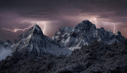 Schneebedeckte Gebirgskette unter Gewitterhimmel mit hellen Blitzen im Winter - ADSF21533