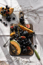 Top view of delicious sweet fruits placed on old wooden chopping board on table in cozy kitchen - ADSF21551