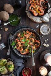 Top view of bowl with appetizing prawns with lemon and parsley served on wooden table with various ingredients for dinner - ADSF21554