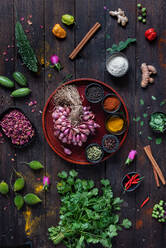 Top view of various seasonings and greenery arranged on wooden table in kitchen - ADSF21555