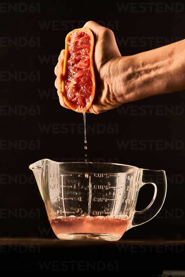 https://us.images.westend61.de/0001535027pw/unrecognizable-crop-person-squeezing-ripe-grapefruit-juice-in-glass-measuring-jug-placed-on-table-on-black-background-ADSF21571.jpg