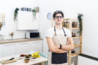 Man wearing apron standing in kitchen - GIOF11744