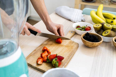 Man chopping fresh strawberries in kitchen - GIOF11749