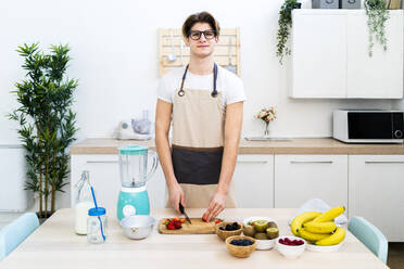 Young man preparing smoothie in kitchen - GIOF11750
