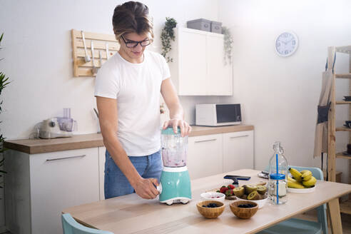 Young man preparing smoothie in kitchen - GIOF11774