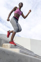 Weibliche Athletin läuft auf Stufen hinunter - RFTF00019