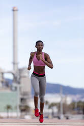 Determined female athlete running on road while looking away - RFTF00022