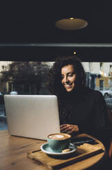 Businesswoman using laptop while sitting in coffee shop - DAMF00741