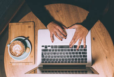 Female professional typing while using laptop in coffee shop - DAMF00747