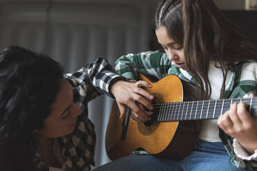 Mutter bringt ihrer kleinen Tochter bei, wie man akustische Gitarre spielt - JAQF00383