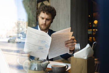 Männlicher Unternehmer prüft Strategie, während er im Café sitzt, gesehen durch Glas - VPIF03701