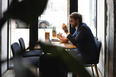 Businessman having food while sitting at cafe - VPIF03704