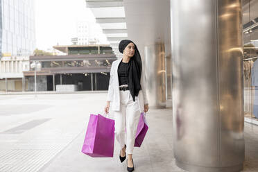 Junge arabische Frau schaut beim Einkaufen im Einkaufszentrum weg - JCCMF01441