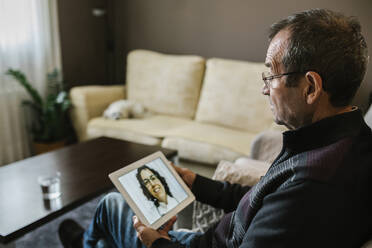 Smiling female doctor on video call consultation with senior male patient at home during COVID-19 - XLGF01340