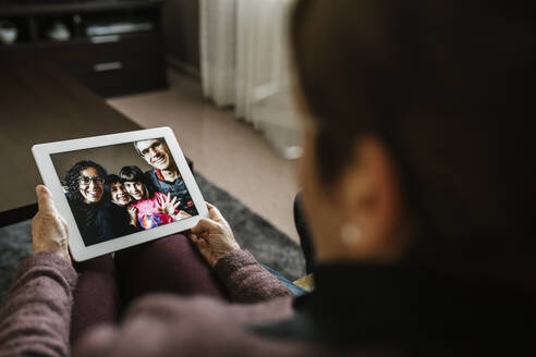 Ältere Frau bei einem Videogespräch mit ihrer Familie zu Hause während COVID-19 - XLGF01344