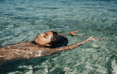 Crop of Junge entspannt am Strand im Sommer, während schwimmend auf dem Meer Wasser - ADSF21739