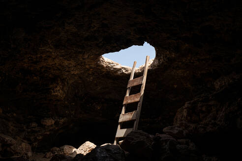 View of the inside of a cave with stairs leading to the outside through a hole - ADSF21741