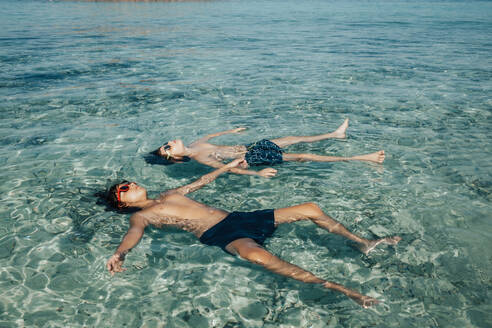 Zwei Jungen entspannen sich im Sommer am Strand, während sie auf dem Meerwasser schwimmen - ADSF21742