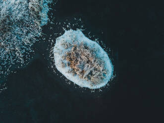 Spektakuläre Drohnenansicht einer kleinen Insel mit Schnee im Meer im Winter - ADSF21751