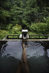 Beine und Füße einer kaukasischen Reisenden, die ein Thermalwasserbad im japanischen Onsen genießt, Blick von oben - ADSF21797