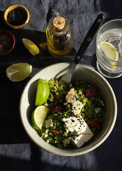 Von oben Schüssel mit Brokkolisalat mit Couscous auf dunkler Stoffserviette - ADSF21817