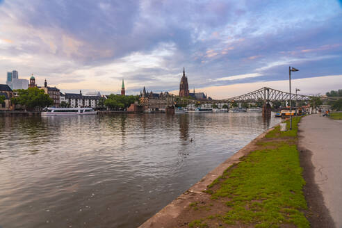 Germany, Hesse, Frankfurt, Riverbank promenade at dusk with Eiserner Steg bridge in background - TAMF02906