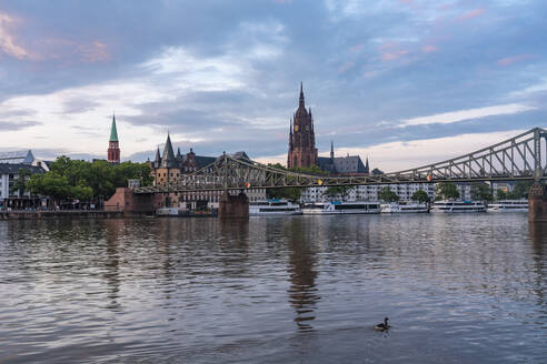 Germany, Hesse, Frankfurt, River Main at dusk with old town and Eiserner Steg bridge in background - TAMF02907