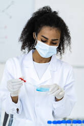 Junge Forscherin beim Testen einer Flüssigkeit im Chemielabor während COVID-19 - GIOF11840