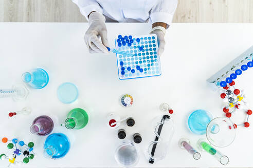 Eine Forscherin entnimmt ein Reagenzglas aus einer Mikroplatte auf einem Tisch im Labor - GIOF11852
