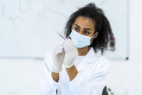 Eine Forscherin untersucht ein Reagenzglas im Labor während einer Pandemie - GIOF11858
