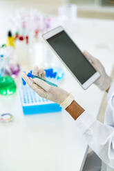 Forscher hält Reagenzglas und digitales Tablet im Labor - GIOF11861