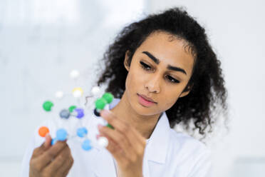 Young female researcher examining molecular structure in laboratory - GIOF11882