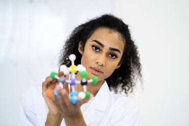 Young researcher holding molecular structure in laboratory - GIOF11883