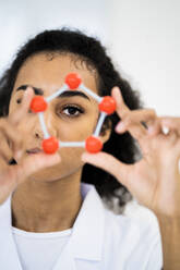 Female researcher looking through molecular structure in laboratory - GIOF11886