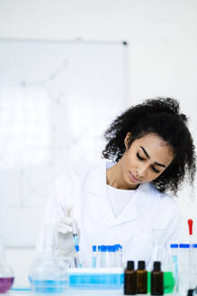 Junger Forscher beim Einspritzen einer Flüssigkeit in ein Reagenzglas im Labor - GIOF11887