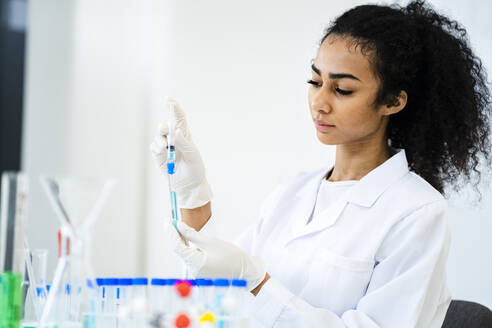 Junge Forscherin beim Einspritzen einer Flüssigkeit in ein Reagenzglas im Labor - GIOF11892