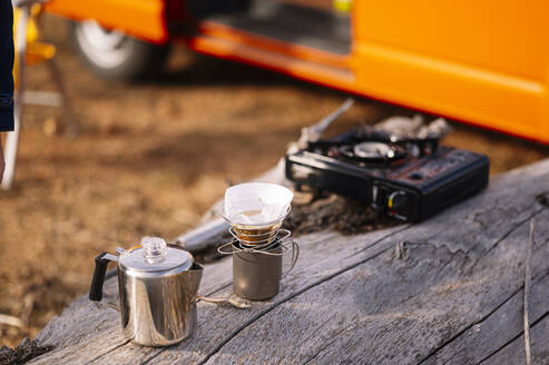 Wasserkocher mit Kaffeetasse und Campingkocher auf Holzblock - JCMF01922