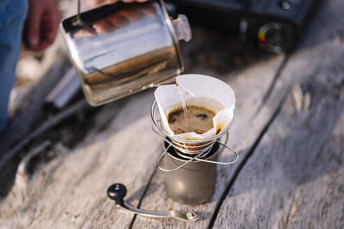 Mann gießt Wasser in einen Wasserkocher und bereitet Kaffee zu - JCMF01923