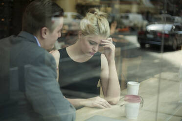 Businessman consoling sad female colleague in cafe - AJOF01272