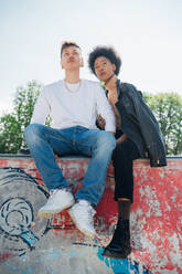 Junges Paar sitzt im Skateboardpark und schaut weg - MEUF02151