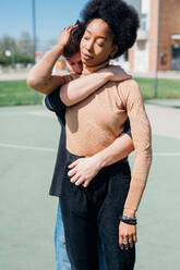 Junger Mann, der seine Freundin von hinten umarmt, während er auf dem Sportplatz steht - MEUF02165