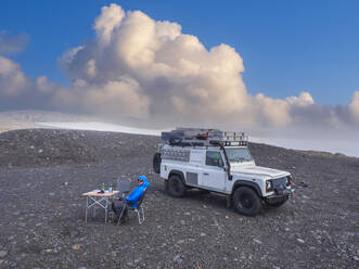 Mann zeltet vor einem Geländewagen an der Küste der Myrdalsjokull-Eiskappe - LAF02693