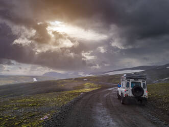 Dramatischer Himmel über einem Geländewagen auf einem abgelegenen Feldweg im Fjallabak-Naturreservat - LAF02699