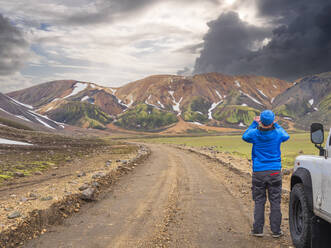 Männlicher Reisender, der die vulkanische Landschaft von Landmannalaugar fotografiert - LAF02700