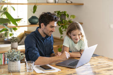 Glücklicher Vater und Tochter mit Blick auf den Laptop - SBOF03291