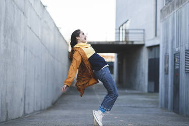 Side view of content female teenager in casual clothes having fun on city road while looking forward - ADSF21945