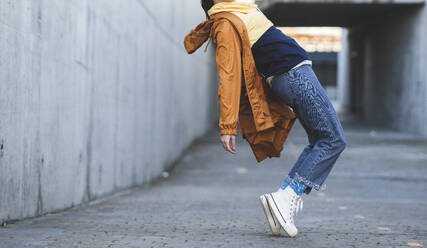 Seitenansicht eines abgeschnittenen, nicht erkennbaren weiblichen Teenagers in Freizeitkleidung, der sich auf einer städtischen Straße amüsiert und dabei nach vorne schaut - ADSF21946