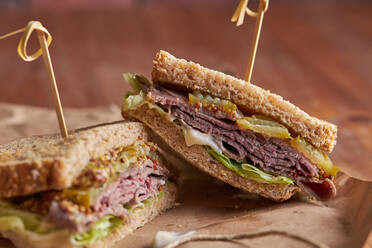 Nahaufnahme eines leckeren Sandwiches mit Pastrami, Salat, Schinken und Gurken - ADSF21985