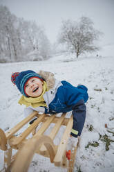 Fröhlicher Junge beim Schlittenfahren im Schnee - MFF07635